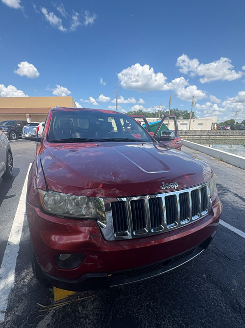 Red 2011 Jeep Grand Cherokee with front-end damage, junked in Fort Myers, FL
